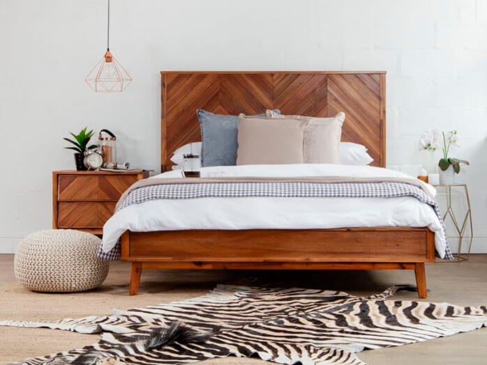 Front view of acacia wooden bed and pedestal on zebra hide